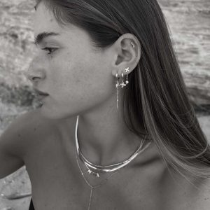 Model showcasing the Flora Earrings Set featuring tiny pearls and gold flowers in a layered style.