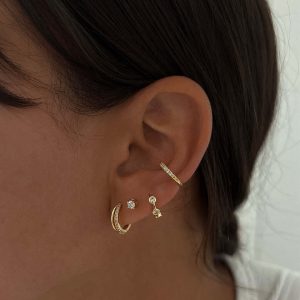 Elle Earrings worn in multiple ear piercings showcasing gold and diamond designs.