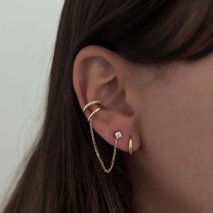 Joy Earring featuring a crystal ear cuff, delicate chain, and gold color for trendy ear styling.