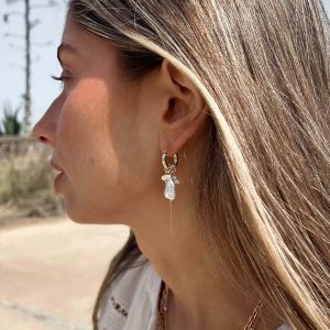 Close-up of a woman wearing Lotus Earrings with removable charms and delicate drop design.