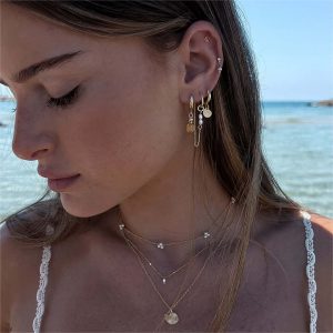 Model wearing the Kai Double Necklace along the beach, showcasing its boho-chic style with shells and pearls.