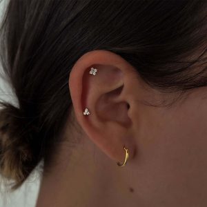 Close-up of a person's ear featuring Crystal Triangle Earrings and a small hoop earring, showcasing modern jewelry style.