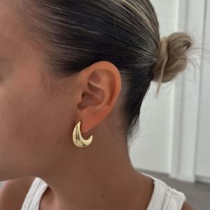 Woman wearing sleek gold Adele Earrings, showcasing their chunky and sculpted design for polished style.