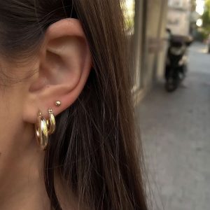 Close-up of a model wearing Baby Boomerang Earrings, classic thicker style hoop earrings.