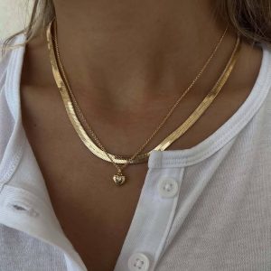 Billy Necklace worn with other gold chains on a person's neck, enhancing their outfit with bold style.