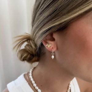 Close-up of a woman wearing Butterfly Wings Earrings with a delicate butterfly design and pearl accents.