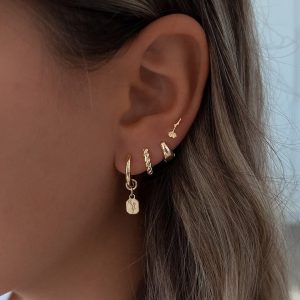 Close-up of a model wearing Calanit Earrings and other gold ear piercings in a delicate floral design.