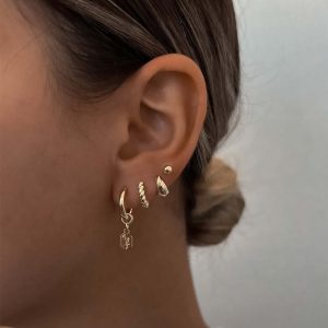 Close-up of a model wearing Calanit Earrings Set featuring classic hoops and anemone studs in a stylish ear stack.