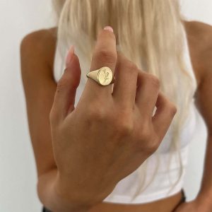 A woman wearing the Kalanit Ring (Anemone), a gold signet ring engraved with an anemone design.