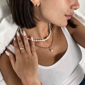 Woman wearing a Candy Necklace with bold freshwater pearls layered with gold jewelry.