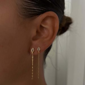 Close-up of a model wearing Raz Earrings with gold chain details.