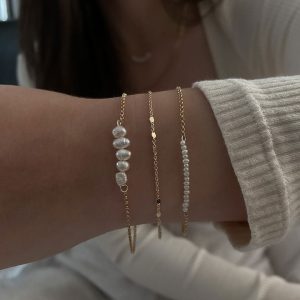 Eli Bracelet worn on a wrist, featuring delicate gold chains and pearls, highlighting its timeless elegance.
