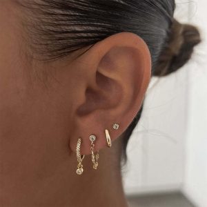 Close-up of a model wearing the Alle Earrings Set showcasing delicate gold hoops and studs.