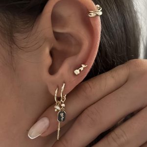 Close-up of delicate Gali Earrings featuring a freshwater pearl and a rose-engraved charm on a model's ear.