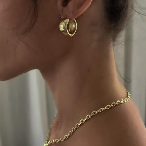 A close-up of a woman wearing Hailey Earrings, bold lightweight gold hoops that add major style impact.