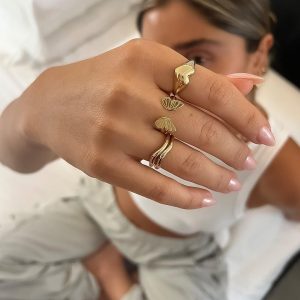 Heart Ring featuring intricate gold designs worn on a hand with polished nails, showcasing elegance and style.