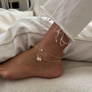 Julie Anklet featuring 14K gold plated brass, freshwater pearls, and a stylish design on a woman's ankle.