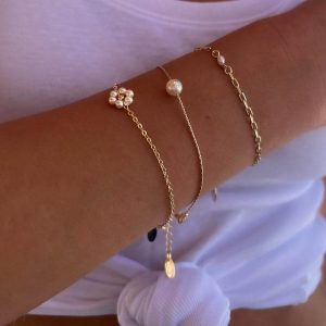 Lee Bracelet featuring delicate gold chains and pearl accents worn on a model's wrist.