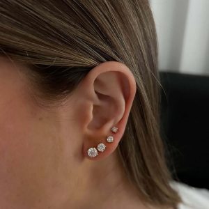 Lenny Round Crystal Earrings showcased on an ear, featuring three sizes of sparkling minimalist studs.