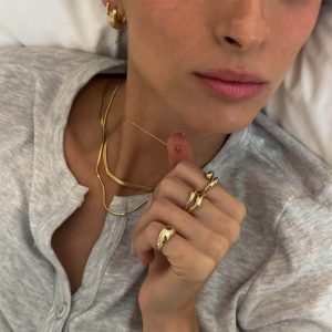 Model wearing Initial Necklaces Set with delicate layers and gold accessories, showcasing trendy jewelry style.