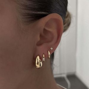Close-up of a model wearing the Lauren Earrings Set, showcasing five delicate earrings in gold.