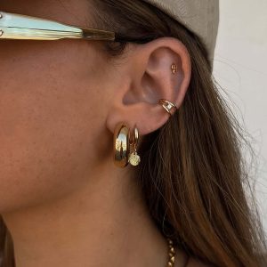 Close-up of a model wearing Kai Earrings featuring hoop design and a delicate shell charm for a coastal vibe.