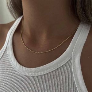 Close-up of a person wearing a gold Tiny Mali Necklace layered on a white tank top, showcasing its dainty elegance.