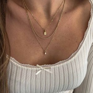 Close-up of a woman wearing the Nice Necklace, featuring three stylish layered gold chains for a bold look.