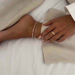 Woman wearing Peacock Anklets on her ankle, showcasing the 14K gold plated brass and freshwater pearls.