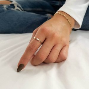 A hand showcasing the Poly Ring with a delicate chain design and a freshwater pearl, perfect for everyday elegance.
