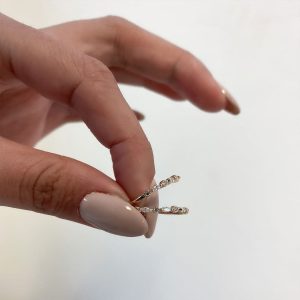 A hand holding the Raz Ring, showcasing its delicate crystal design and elegant style.