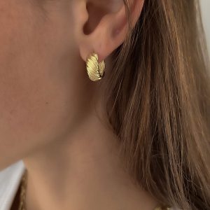 Close-up of a woman's ear wearing gold Reef Earrings, showcasing clean lines and bold design.