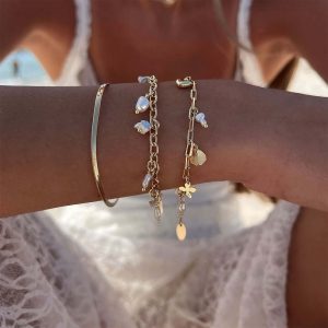 Beautiful arms displaying the Story Bracelet with pearls, charms, and a gold chain for a feminine look.