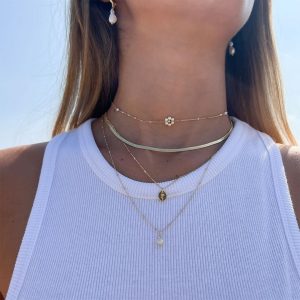 Sol Necklace Set featuring layered delicate gold necklaces with floral and unique designs worn by a model.