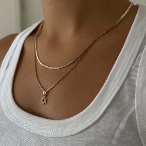 Star of David Necklace worn on a person, showcasing craftsmanship in radiant gold, layered with delicate chains.