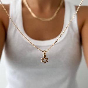 Close-up of a person wearing a Star of David Necklace Set featuring a gold pendant.