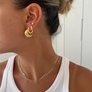 Close-up of a model wearing the Tiny Liz Necklace layered with gold earrings.