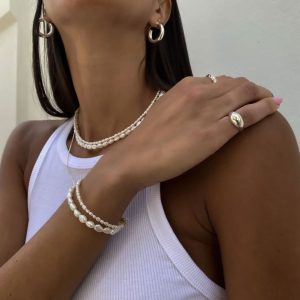 Model showcasing Tommy Earrings - 925 Sterling Silver with pearl jewelry and stylish outfit.