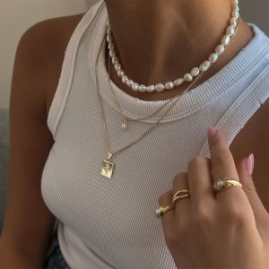 Vintage Pearl Necklace layered with gold chains and rings, showcasing a subtle classic style and elegance.