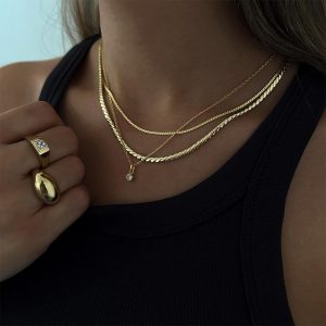 A person wearing layered gold necklaces and a Vintage Crystal Ring, showcasing modern jewelry style.