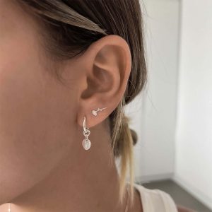 Close-up of a model wearing Wildflower Earrings 925 with an anemone engraving, showcasing nature-inspired jewelry.
